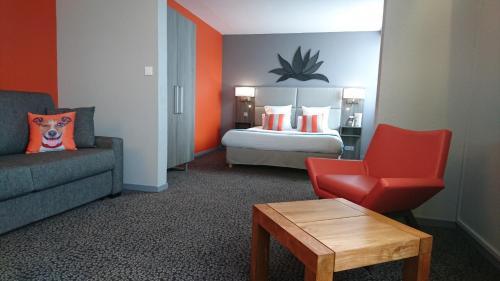 a hotel room with a bed and a couch and a chair at Kyriad Prestige - Bordeaux Aeroport in Mérignac
