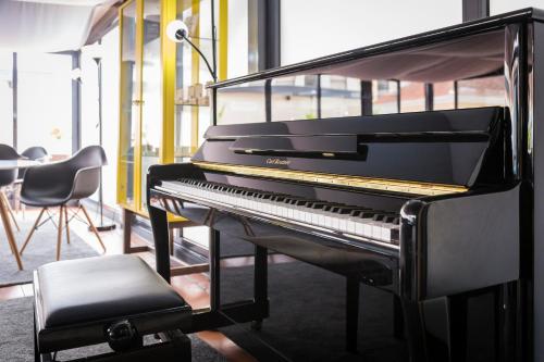 a black piano in a room with a table and chairs at AquaHotel in Ovar