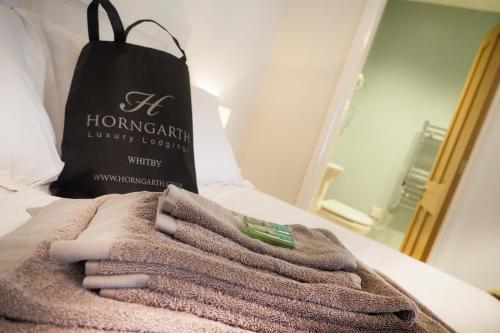 a pile of towels on a bed with a bag at The Horngarth in Whitby