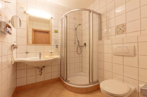 a bathroom with a shower and a toilet and a sink at Hotel Andreas Hofer in Sankt Leonhard im Pitztal