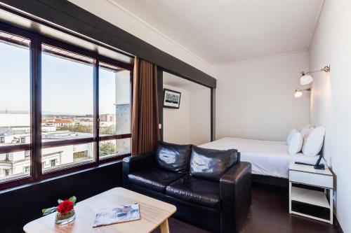 a hotel room with a bed and a couch and a window at AquaHotel in Ovar