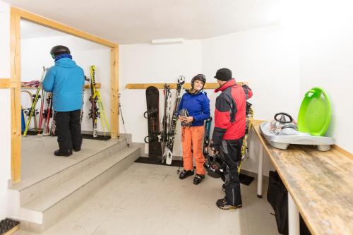 a group of three people standing in a room with skis at Hotel Andreas Hofer in Sankt Leonhard im Pitztal