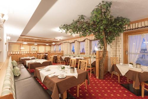 un restaurante con mesas, sillas y un árbol en Hotel Andreas Hofer en Sankt Leonhard im Pitztal