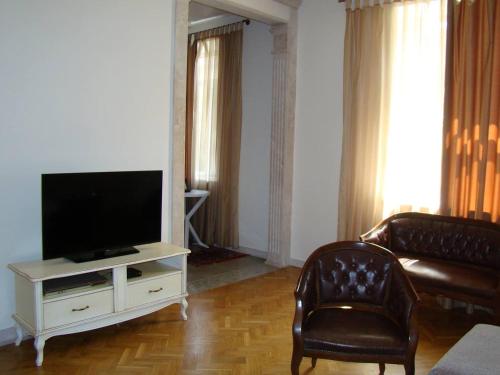 - un salon avec une télévision et deux fauteuils en cuir dans l'établissement Best choice in the heart of Yerevan, à Erevan