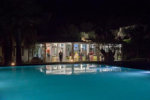 a large blue swimming pool at night with people standing outside at Kalos Relais in Catanzaro