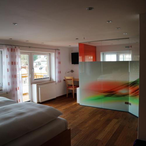 a room with a bed and a glass wall at Hotel Bellevue in Riezlern