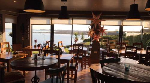 a restaurant with tables and chairs and a view of the ocean at Wildwood Lodge in Carlingford