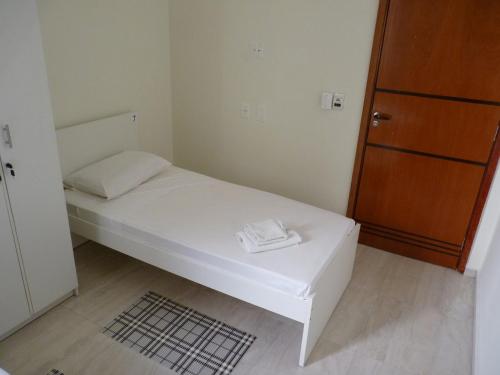 a small bedroom with a white bed and a wooden cabinet at Hostel Casa 77 in Sorocaba