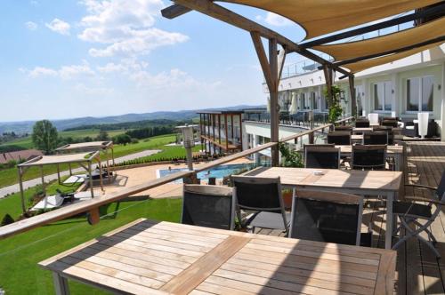 an outdoor patio with wooden tables and chairs and a view at Revita Hotel Kocher in Sankt Agatha