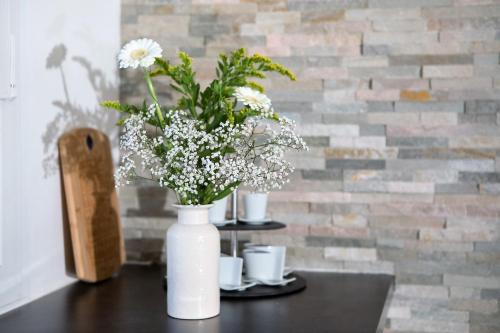 a white vase with white flowers on a table at Gite Bons Amis in Dijon