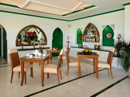 a dining room with tables and chairs and green walls at Villa Esmeralda in Lagos