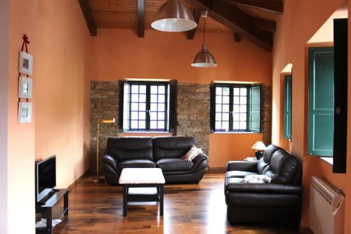 una sala de estar con muebles de cuero negro y paredes de color naranja. en Casa Pedrosa, en Mondoñedo