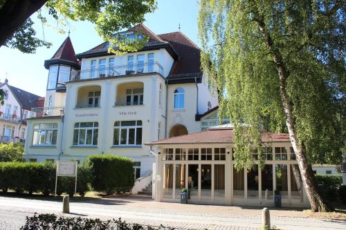 ein großes weißes Gebäude mit einem Uhrturm in der Unterkunft Strandresidenz Villa Verdi in Kühlungsborn