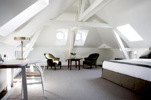 um quarto com uma cama, uma mesa e cadeiras em Le 25bis by Leclerc Briant em Épernay