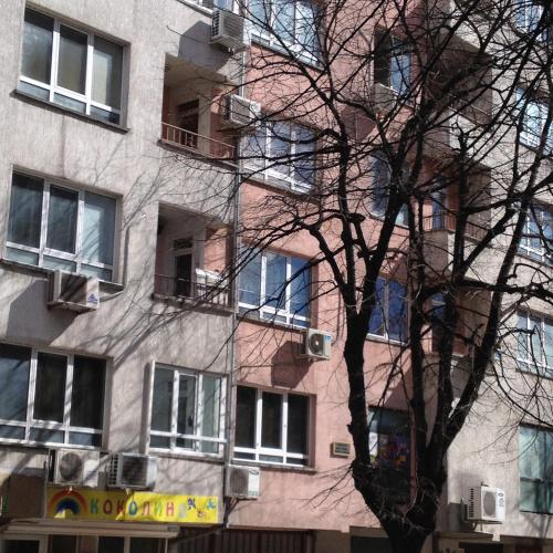 un grand bâtiment avec un arbre devant lui dans l'établissement Apartment Sinchets, à Varna