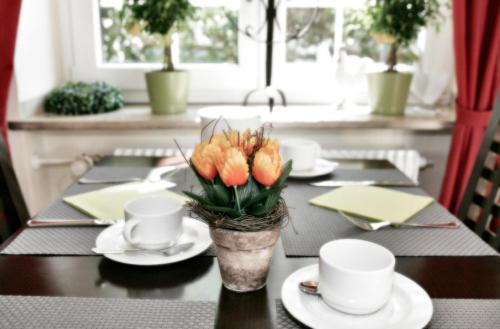 a table with cups and a vase with flowers on it at Hotel Biederstein am Englischen Garten in Munich