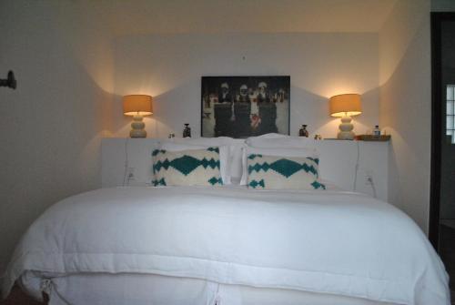 a bedroom with a white bed with two lamps at Maison l'Etrier in Saintes-Maries-de-la-Mer