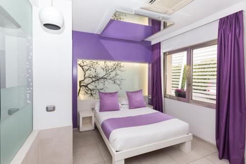 a bedroom with purple walls and a bed with purple pillows at JC Hotel in Rome