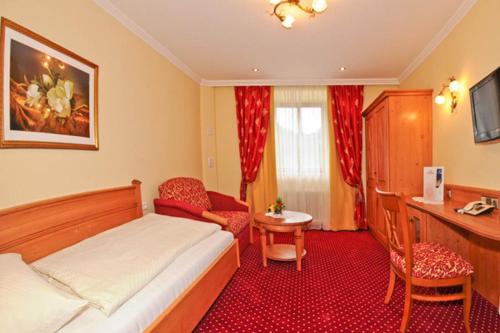 a bedroom with a bed and a desk and a chair at Ferienhotel Gasthof zur Post in Untertauern