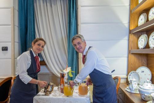 two women are standing at a table with orange juice at Hotel Barocco in Rome
