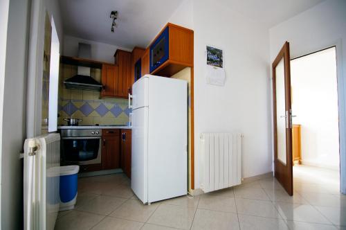 a white refrigerator in a kitchen with wooden cabinets at Apartments Ida Cres in Cres