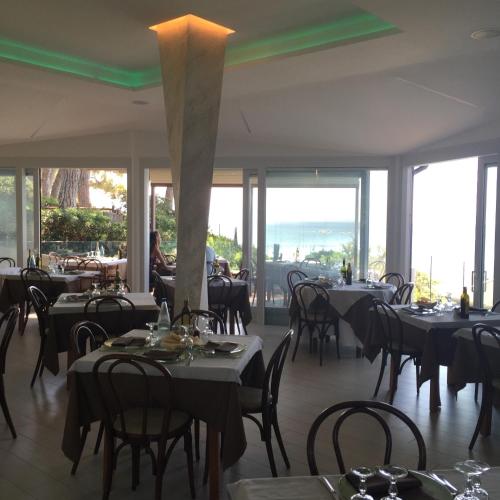 a dining room with tables and chairs and windows at Hotel Boschetto in Follonica