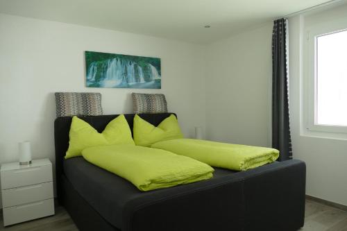 Sofá negro con almohadas amarillas en una habitación en Appartement Butterfly en Saas-Grund