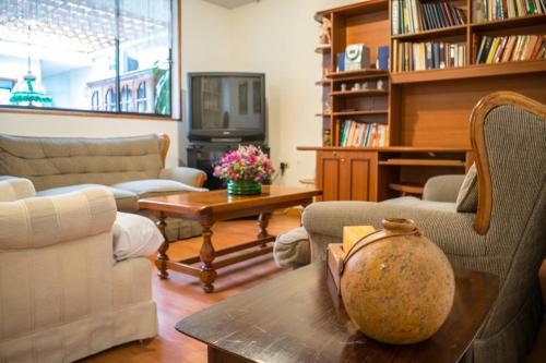 ein Wohnzimmer mit Sofas, einem Tisch und einem TV in der Unterkunft GHL casa hotel in Bogotá