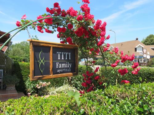 a sign for a family garden with red flowers at Titi Family Apartman in Bük