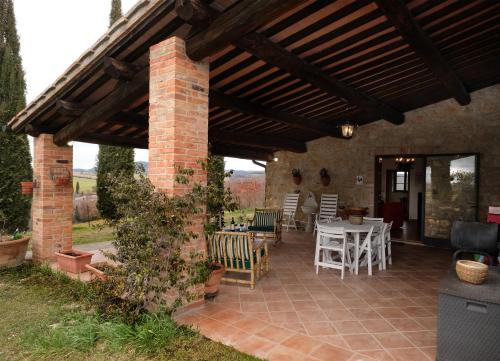 a brick patio with a wooden pergola at Podere Cacchini in Pienza