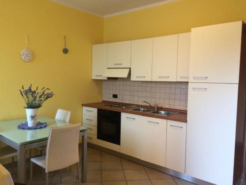 una cucina con armadi bianchi, tavolo e lavandino di Appartamento Riva a Neive