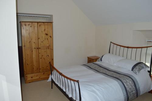 a bedroom with a large bed and a wooden cabinet at Stabl yr Nant in Pentrefoelas