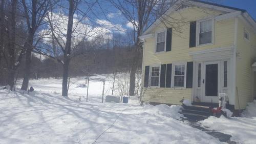 a yellow house with snow in front of it at A Meadow House in Lakeville