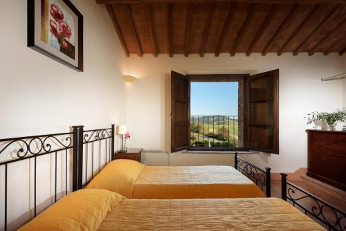 a bedroom with two beds and a window at Podere Ampella in San Giovanni dʼAsso