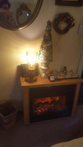 a table with a fireplace with a lamp and a mirror at A Meadow House in Lakeville