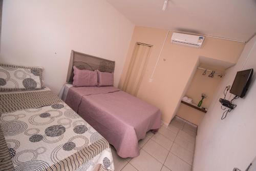 a small room with two beds and a television at Pousada e Restaurante Manaím in Passa e Fica