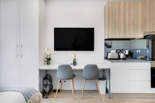 um quarto com uma secretária com 2 cadeiras e uma televisão em Backup-Powered Trendy NY City Apartment at Table Mountain em Cidade do Cabo