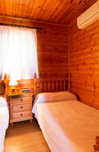 a bedroom with two beds and a window in a log cabin at Hotel y Bungalows Balcón de Competa in Cómpeta