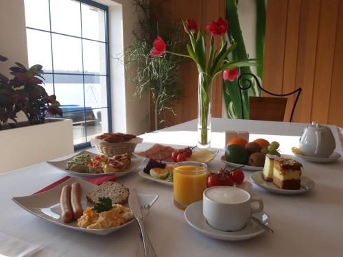 a table with plates of food and a vase with flowers at Hotel Active in Szczecinek