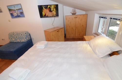 a bedroom with a large white bed and a blue chair at Maritimo Apartments in Kotor