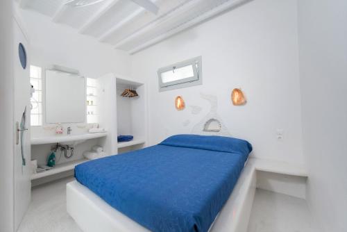 a white bedroom with a blue bed and a sink at Melesio Studios Mykonos Town in Mýkonos City