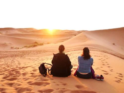 two women sitting in the desert watching the sunset at Riad Dar Ouzine in Merzouga
