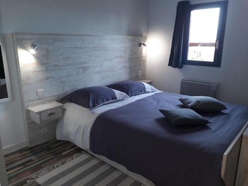 une chambre avec un grand lit avec des draps et des oreillers bleus dans l'établissement Les Soleils de Pontaillac, à Vaux-sur-Mer