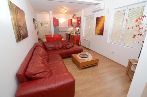 a living room with a red leather couch and a table at Maritimo Apartments in Kotor