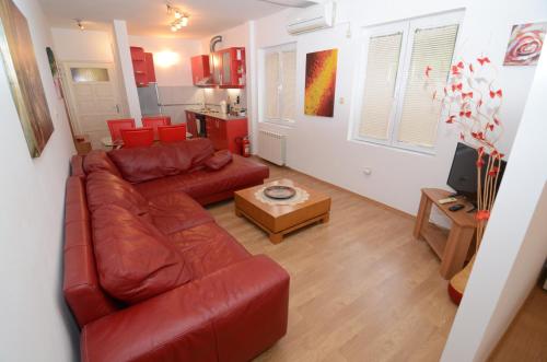 a living room with a red leather couch and a table at Maritimo Apartments in Kotor