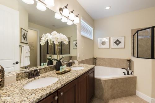 uma casa de banho com 2 lavatórios, uma banheira e um espelho grande em Desert Villa 760-764 em Kissimmee
