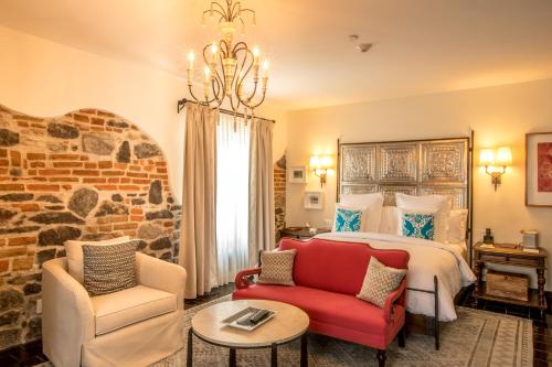 a bedroom with a bed and a couch and a chair at Banyan Tree Puebla in Puebla