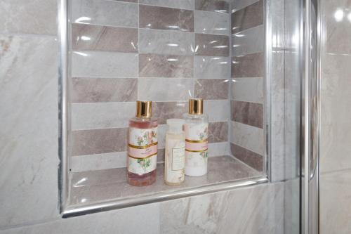 dos botellas están sentadas en una estantería de cristal en un baño en House Maria, en Agios Nikolaos