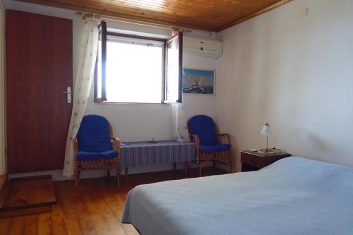 a bedroom with two blue chairs and a bed and a window at Apartmani Surjan in Vela Luka