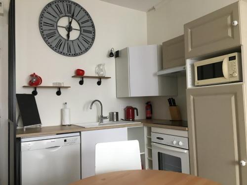 a small kitchen with a clock on the wall at Appartement Erik Satie in Honfleur